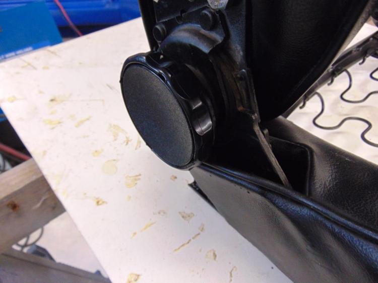 A closeup of the seat recline adjustment knob. The round center section pries out with a small screwdriver. There is a sheet metal piece underneath that must be rotated a few degrees until its release slots line up with the tabs.